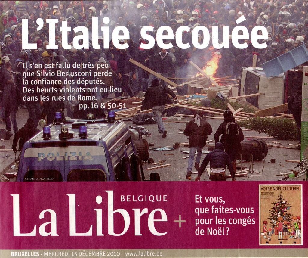 Photo d'émeute à Rome. Dans le fond de l'image, on voit une masse de jeunes masqués. En premier plan, des voitures renversées, des feux boutés.